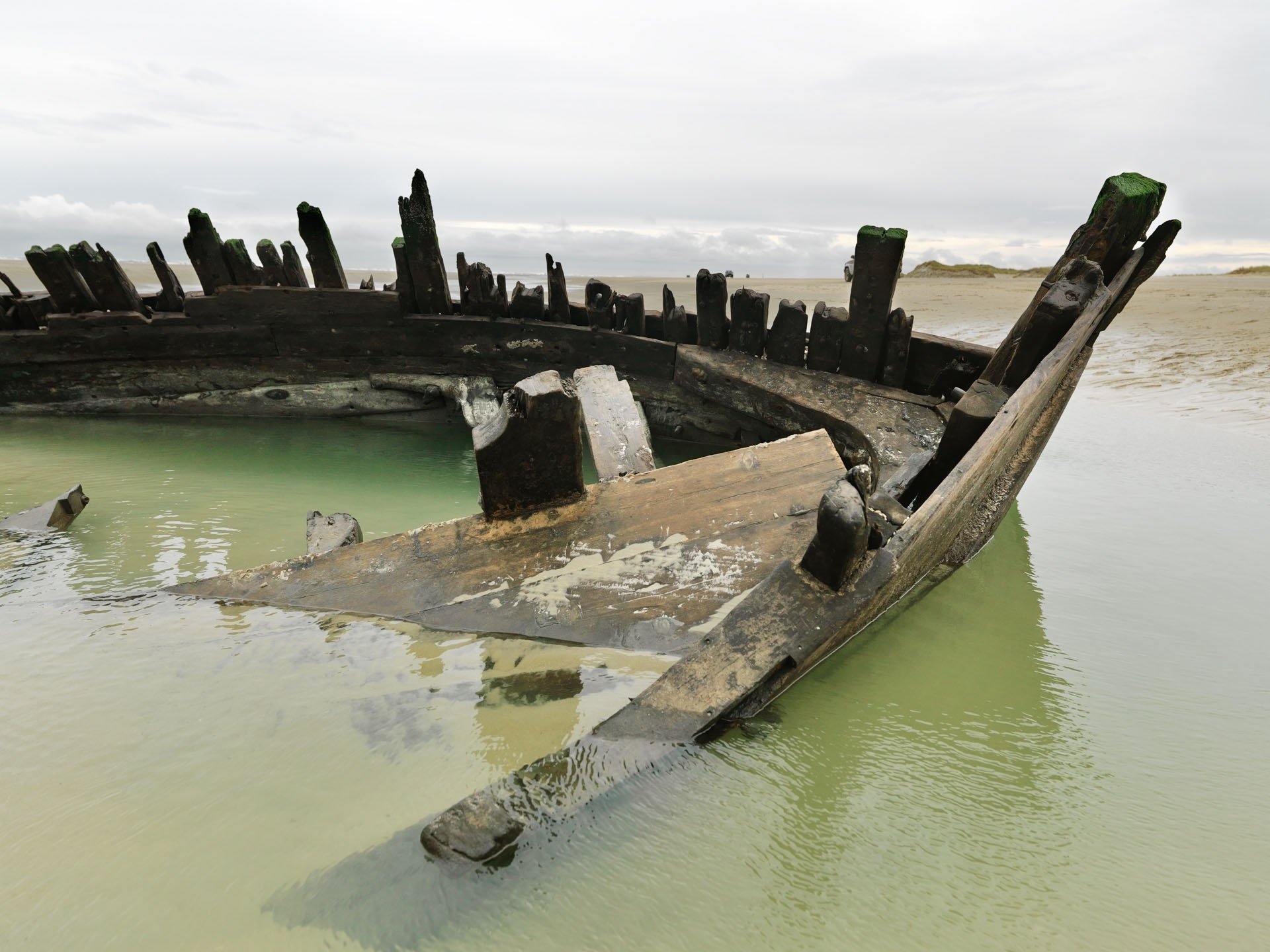 Wooden shipwreck in shallow water on the beach