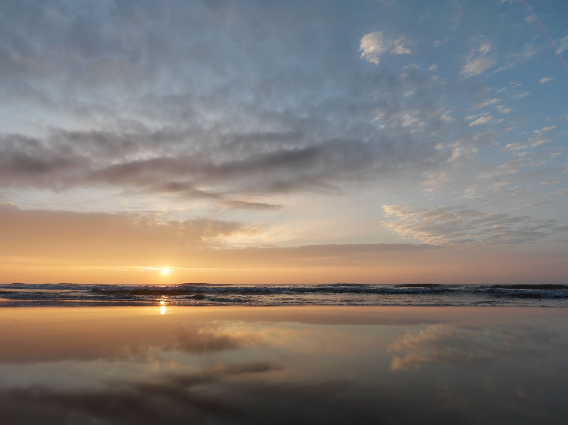 Low sun reflected on a wet beach