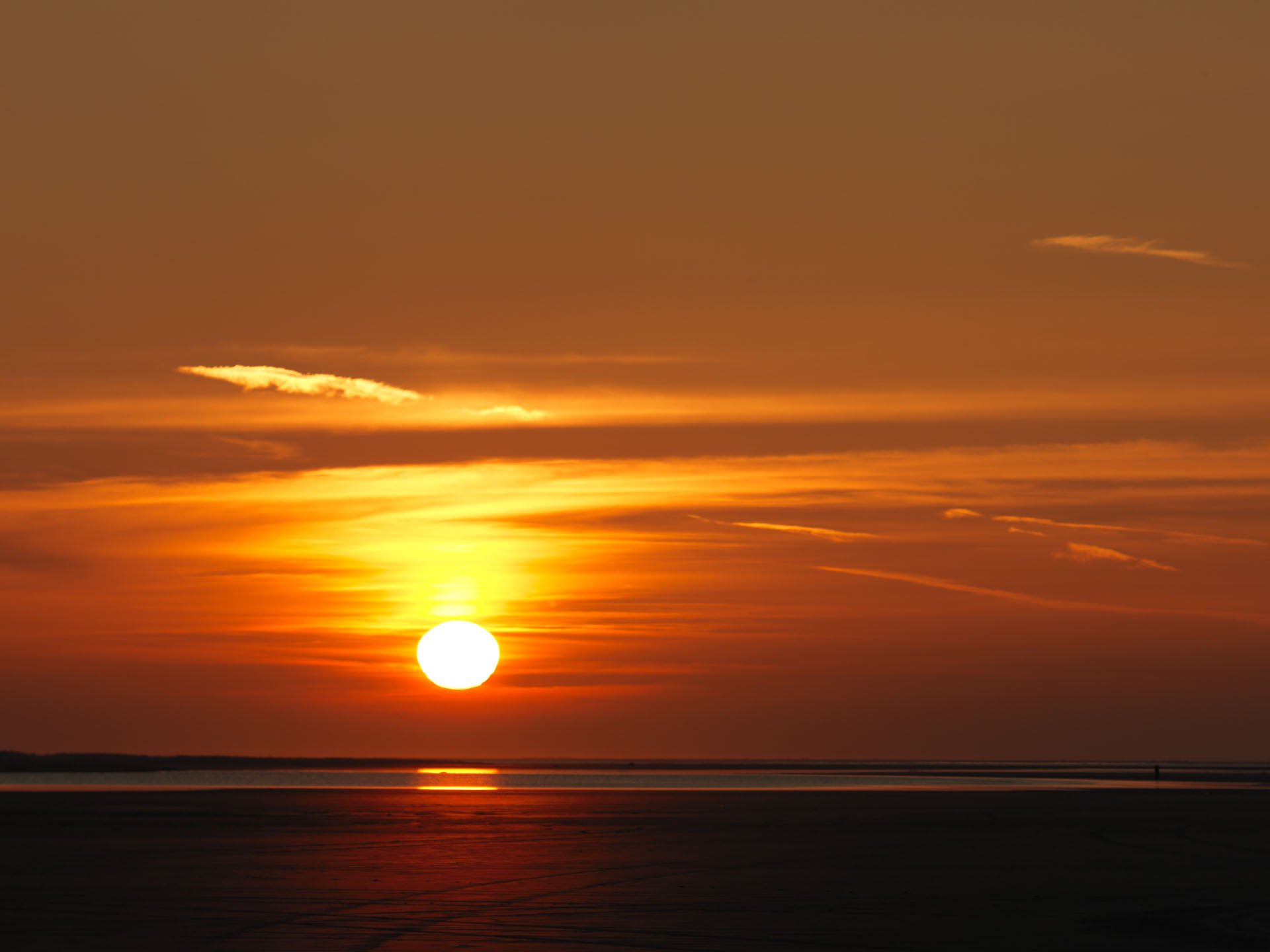 Round orange sun above a dark sea horizon
