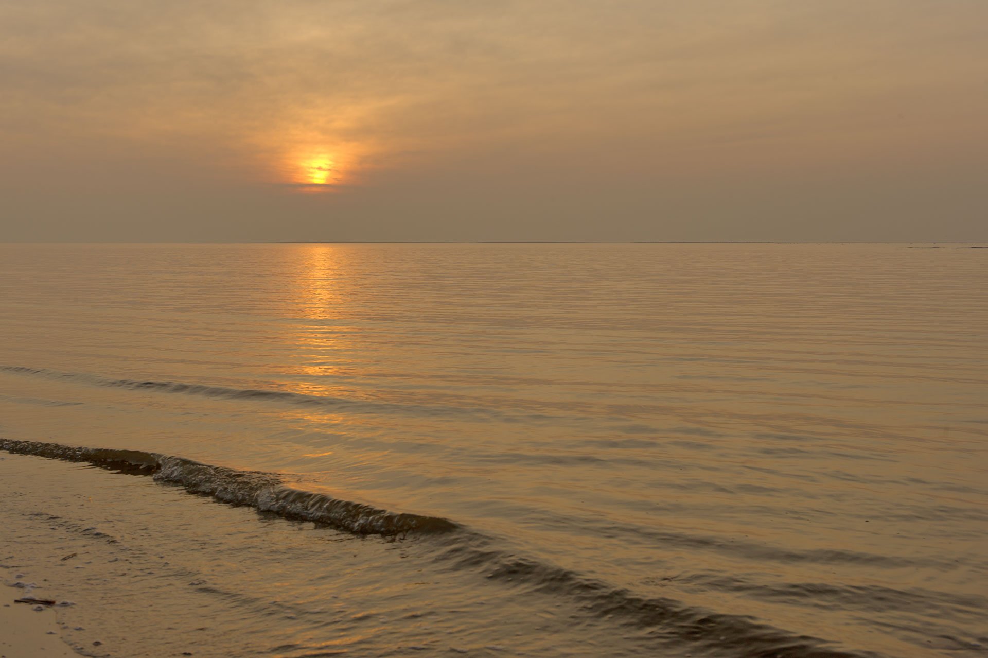 Sunset over calm water and a sandy shore